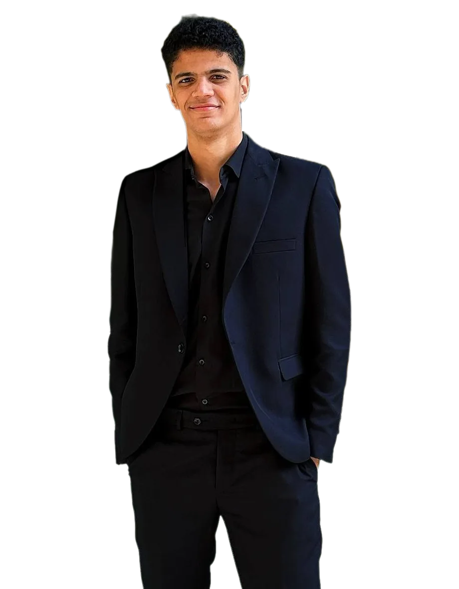 Yassen Ashraf, smiling, in a dark suit with his hands in his pockets.
